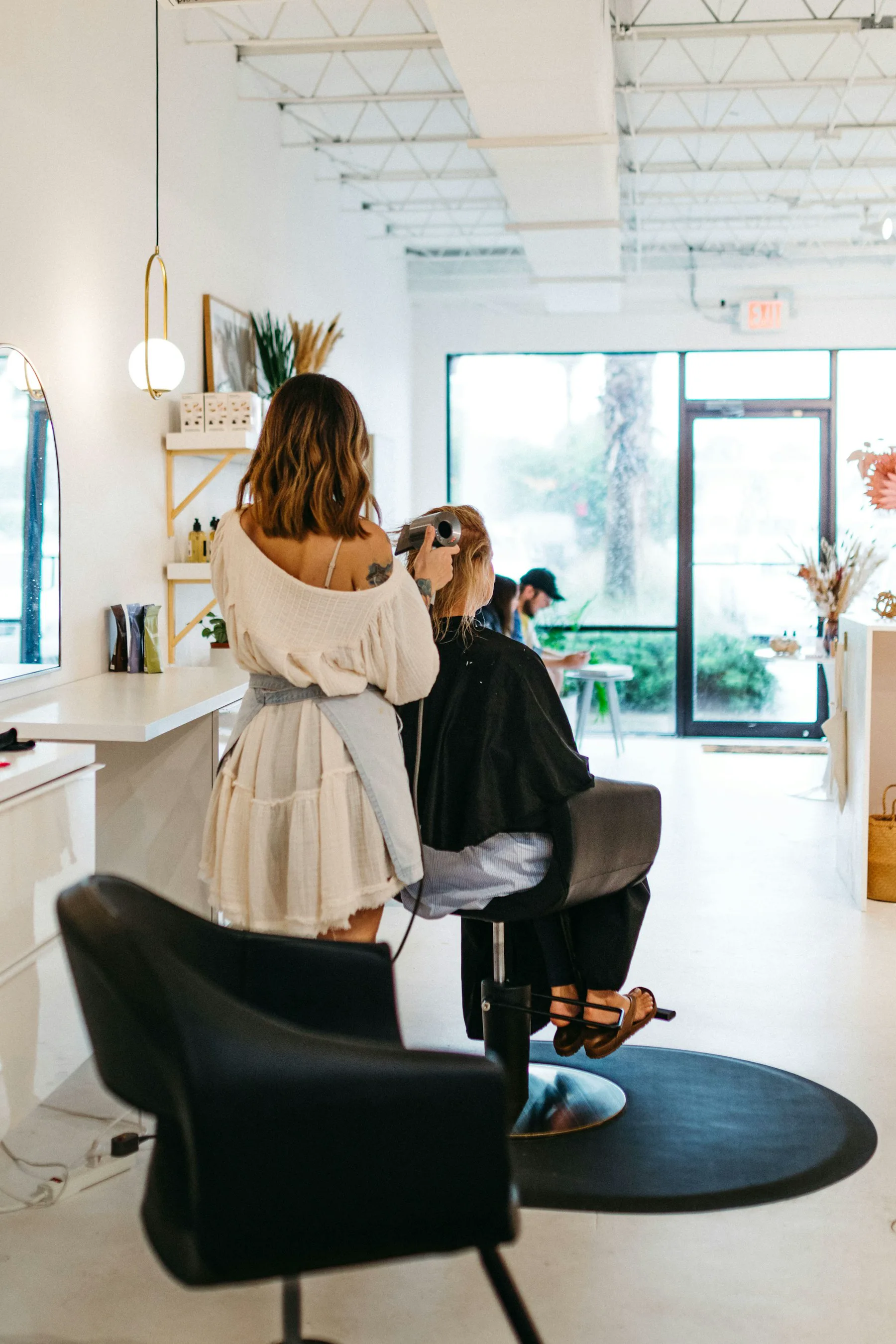 A stylist drying a client's hair in a bright salon