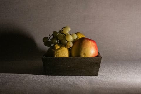A small wooden box of grapes and apples against a dark background